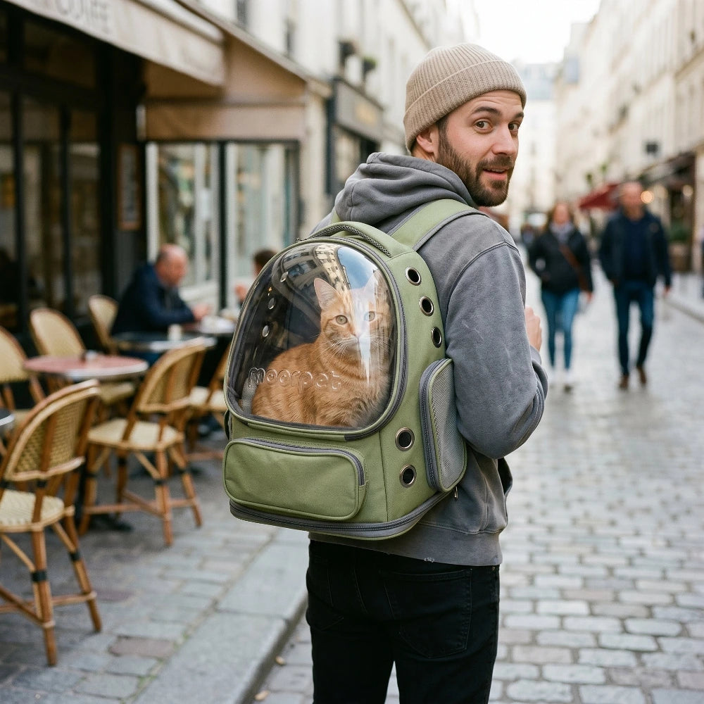 un homme portant un sac a dos pour chat moorpet vert avec un chat à l'interieur aux poils roux