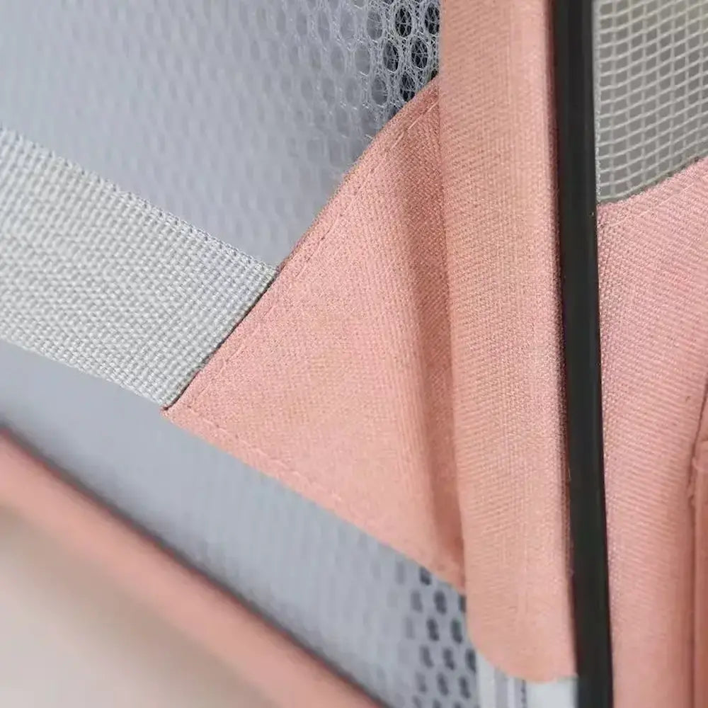 Détail en gros plan des coutures renforcées, de l'attache de sangle et de la maille filet d'un sac de transport rose pour chat.