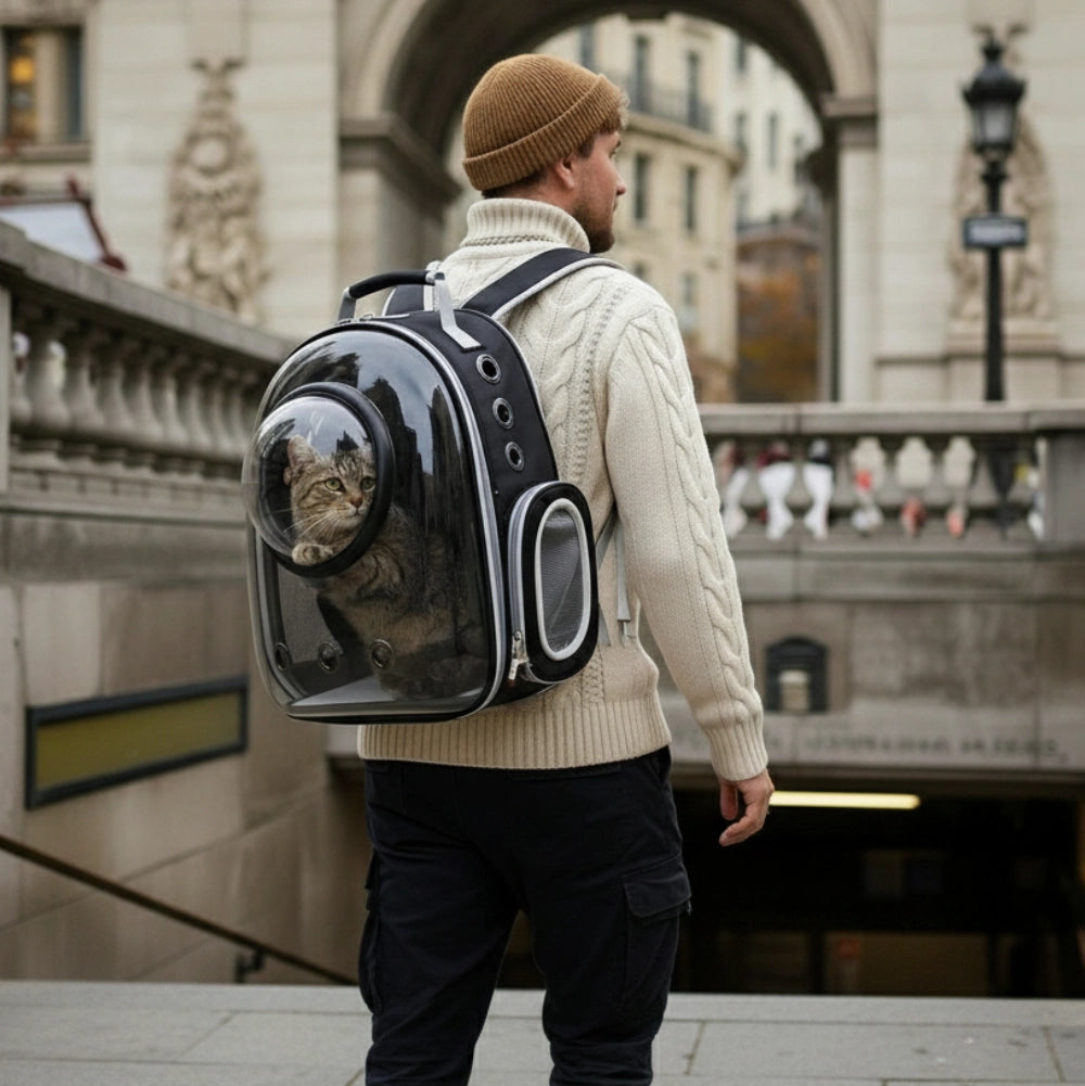 Homme portant un sac à dos de transport pour chat en ville, avec le chat visible derrière la bulle transparente.