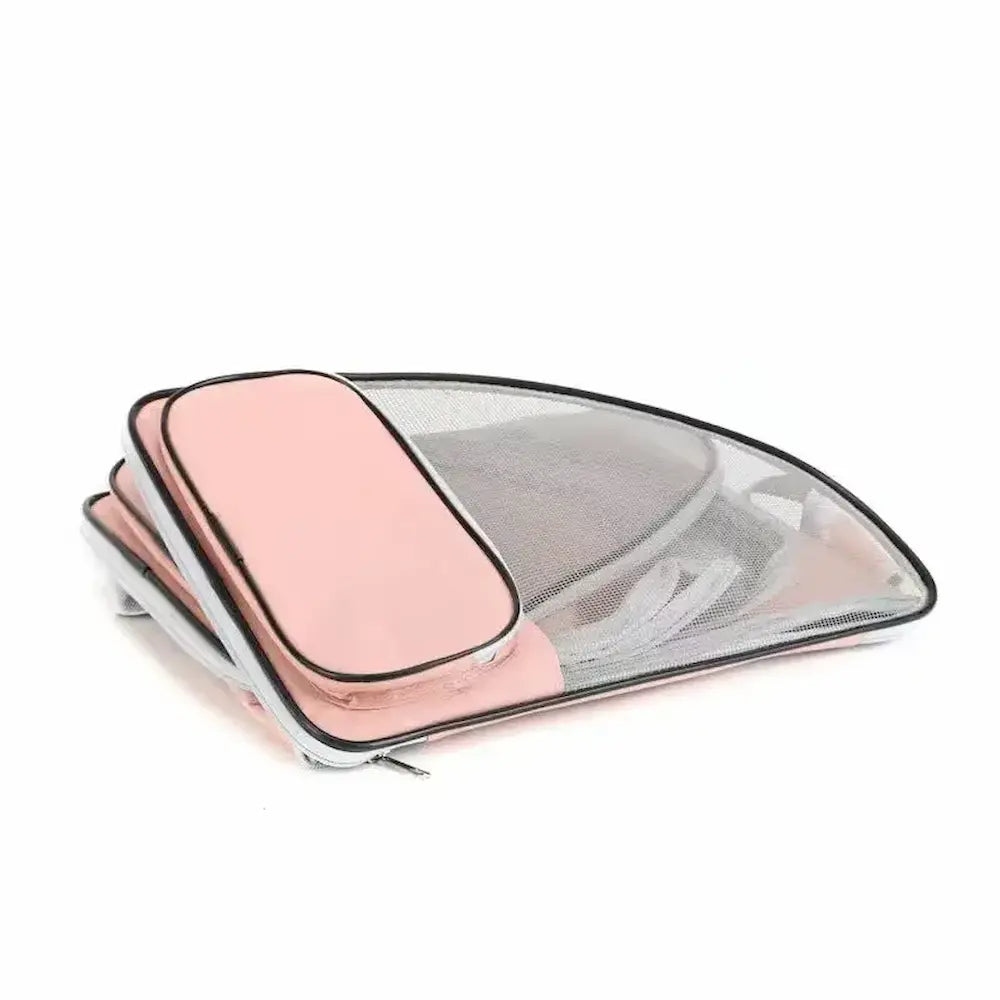 Sac de transport rose pour chat entièrement plié à plat, montrant la pochette de rangement extérieure zippée et la structure souple en maille.